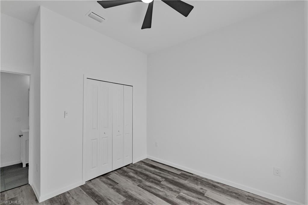 Room featuring wood-finish flooring, a bi-fold closet, and a ceiling fan