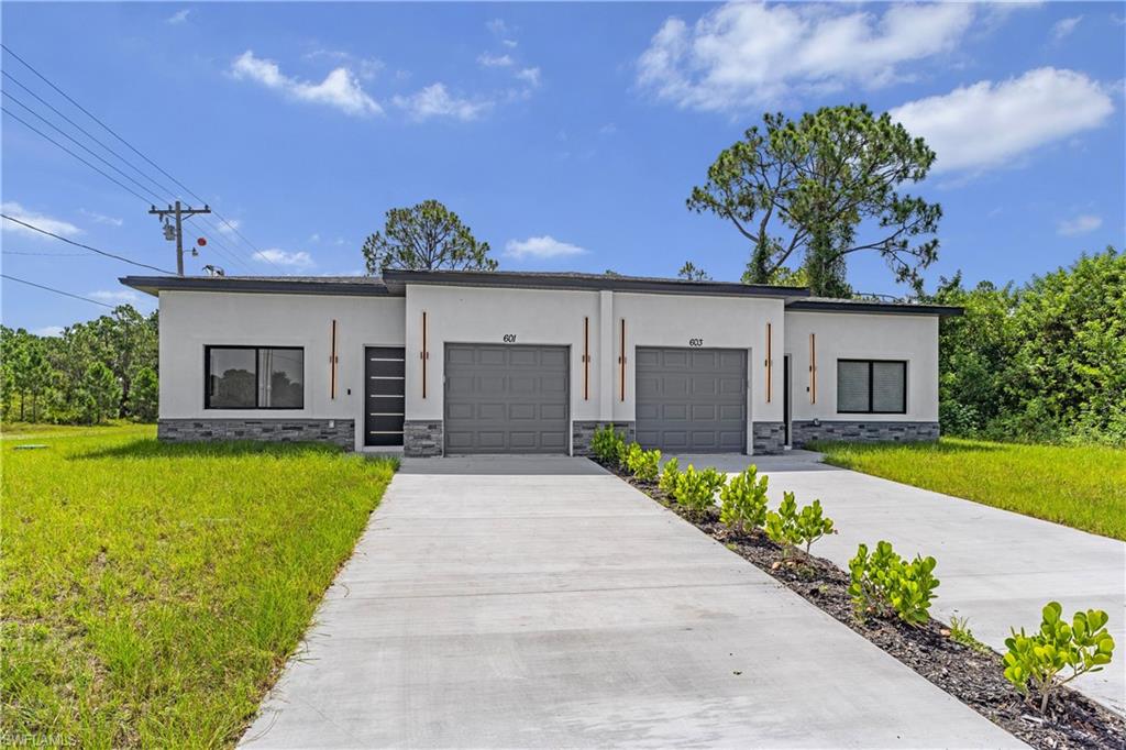 Contemporary duplex featuring a light-colored stucco exterior with dark gray stone veneer accents