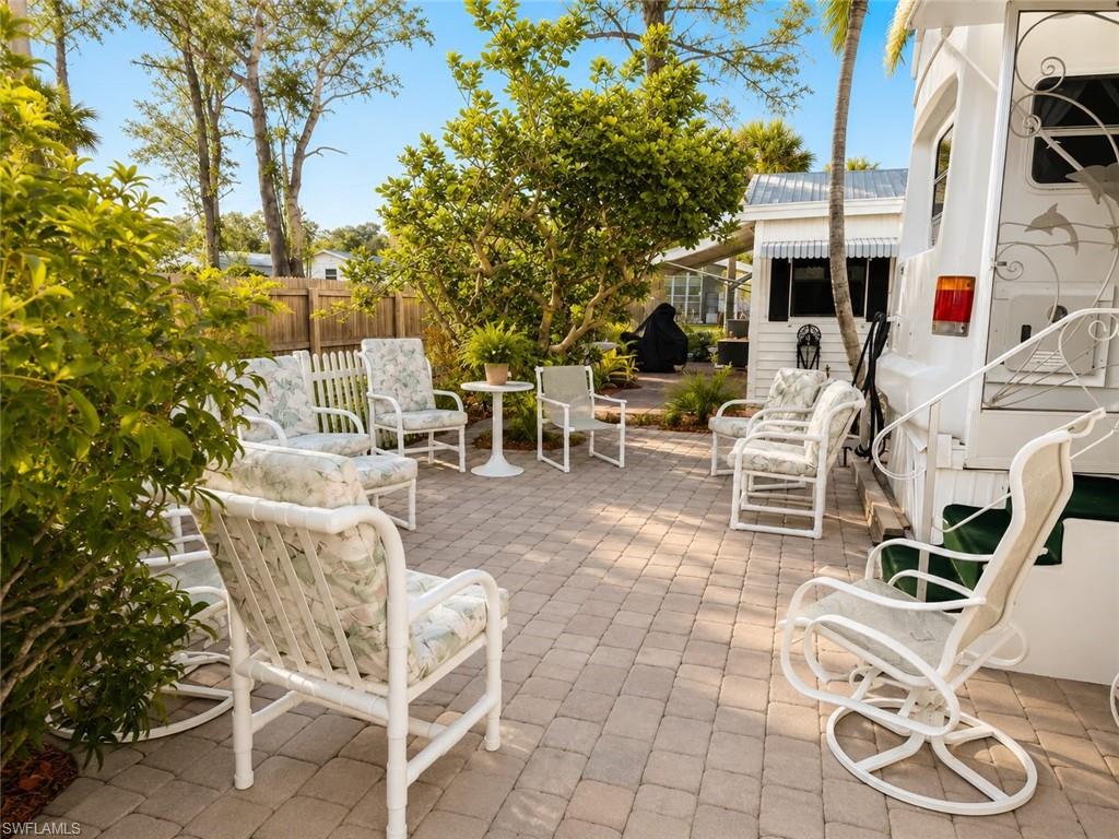 Paver patio featuring a picket fence, lush landscaping, and a white awning