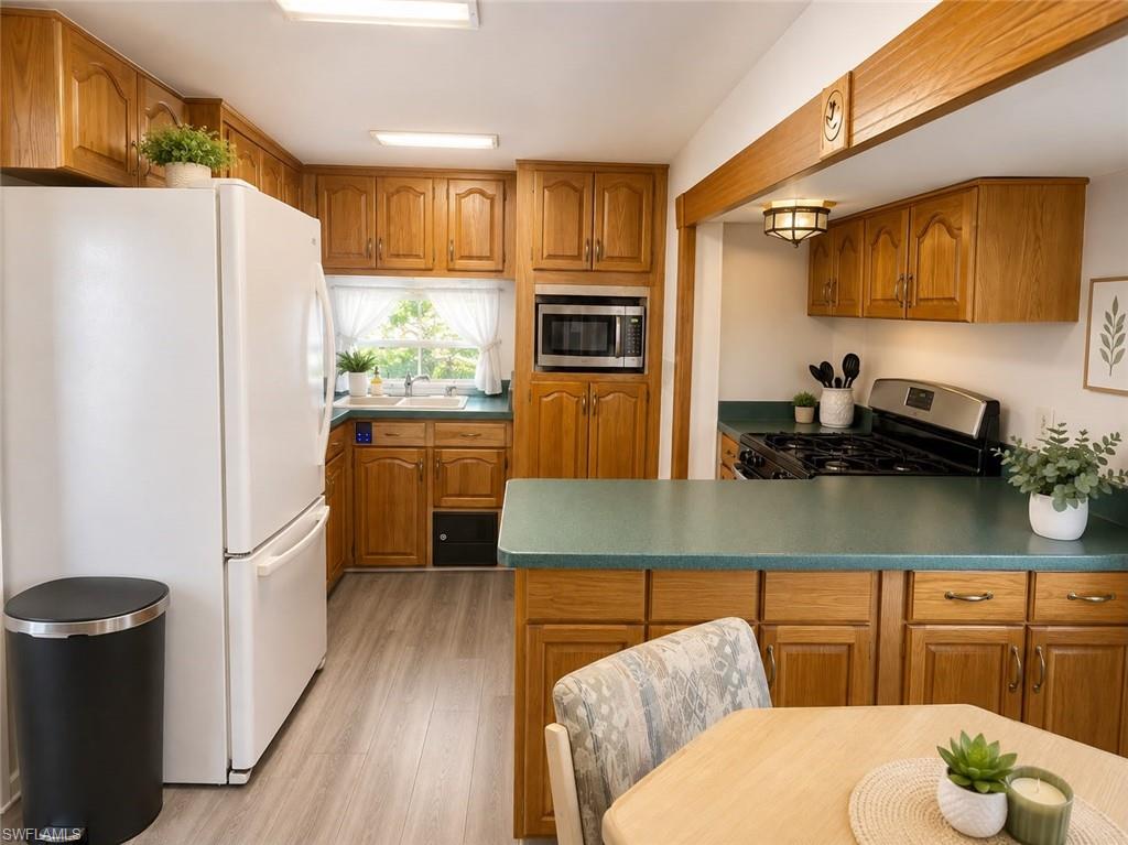 Kitchen featuring wood cabinetry, light-toned flooring, and a built-in microwave