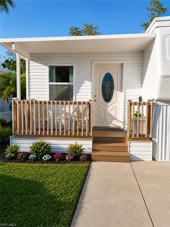 Entryway porch featuring a white oval-inset door with patterned glass, composite wood steps, and a white siding exterior