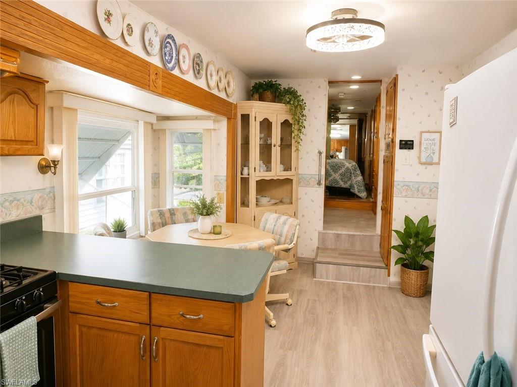 Kitchen with wood-finish flooring, oak cabinetry, and dark countertops