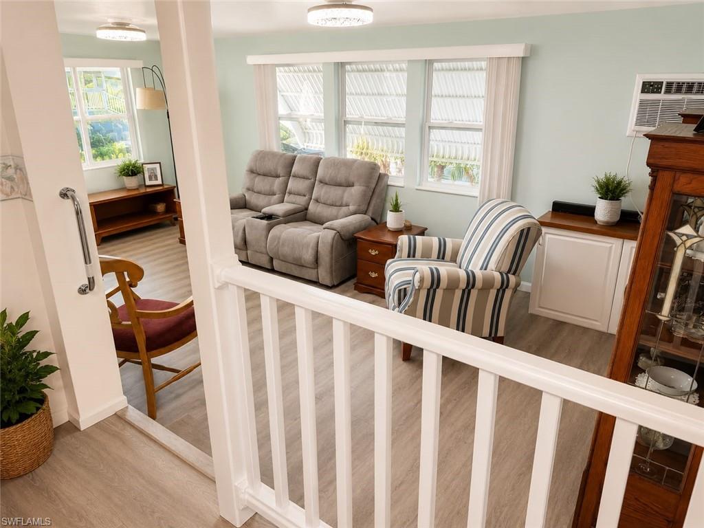 Wood-finish flooring throughout, white balustrade, and ample natural light from multiple windows