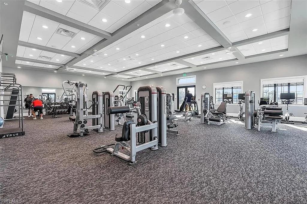Spacious fitness center featuring varied exercise equipment, a drop ceiling with recessed lighting, and expansive windows