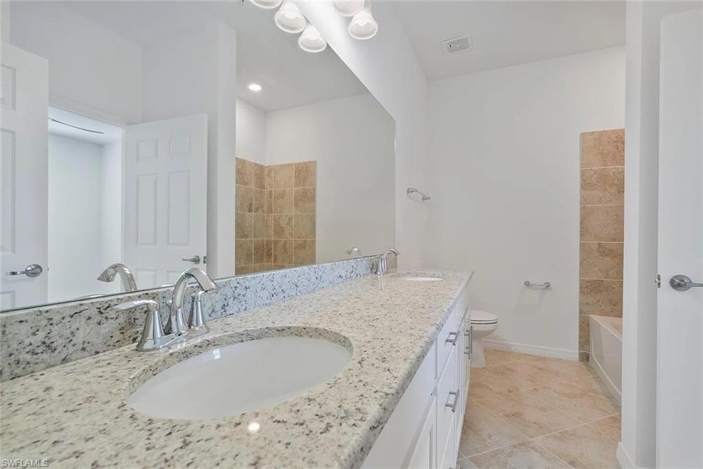 Spacious bathroom featuring a double vanity with granite countertop, dual undermount sinks, and chrome faucets