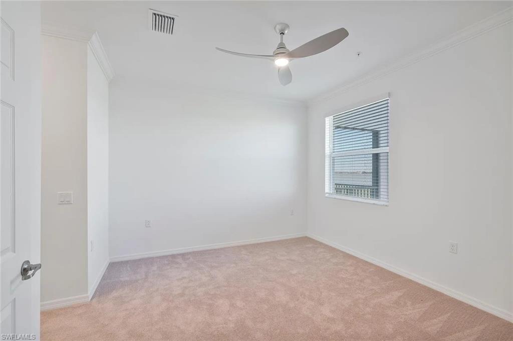 Neutral-toned carpeting extends throughout this room, complemented by white walls and crown molding