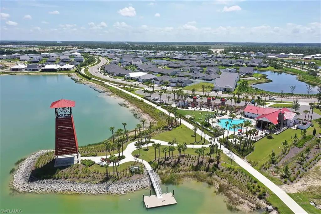 Resort-style amenities featuring a central pool area, a community building with a red roof, and a water tower structure on an island