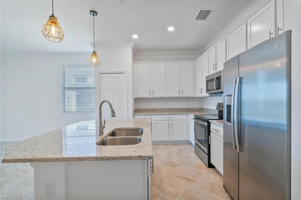 Kitchen featuring a large island with an undermount double basin sink, stainless steel appliances, white cabinetry, and granite countertops