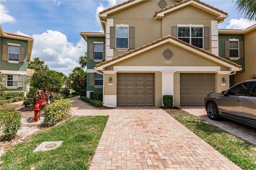 View of front facade with decorative driveway, stucco siding, a tile roof, and an attached garage