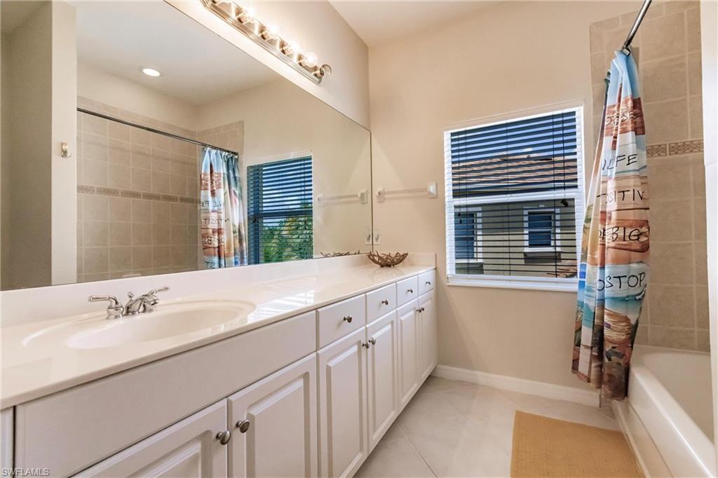 Full bathroom featuring double vanity, shower / bath combination with curtain, and light tile patterned flooring