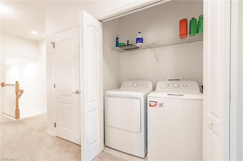 Laundry area featuring light colored carpet and separate washer and dryer