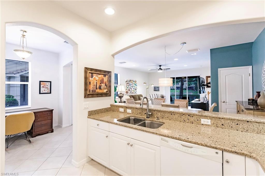 Kitchen featuring hanging light fixtures, light stone counters, and arched walkways