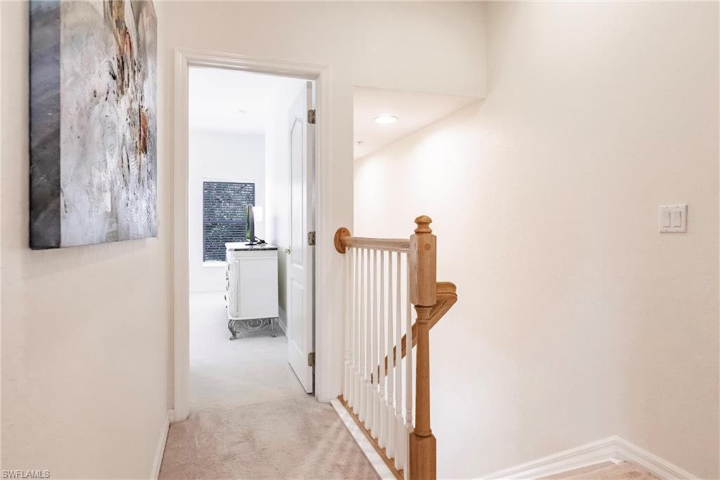 Hallway featuring light colored carpet and an upstairs landing