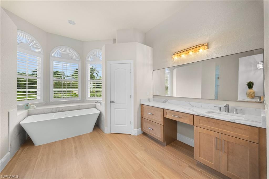 Freestanding soaking tub with a surrounding marble-finish ledge