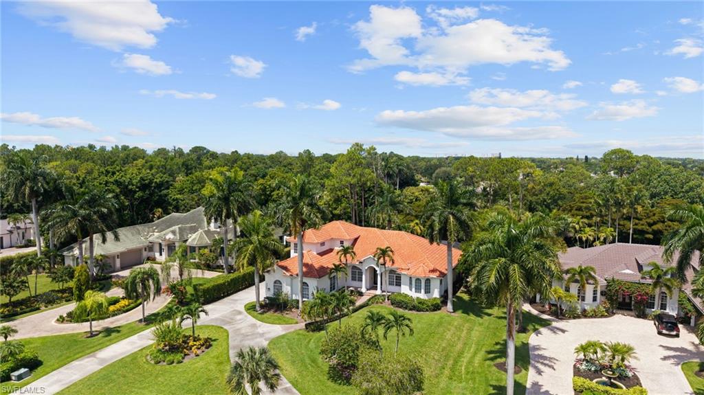 Mediterranean-inspired residence featuring a terracotta tile roof, white stucco exterior, and a circular driveway
