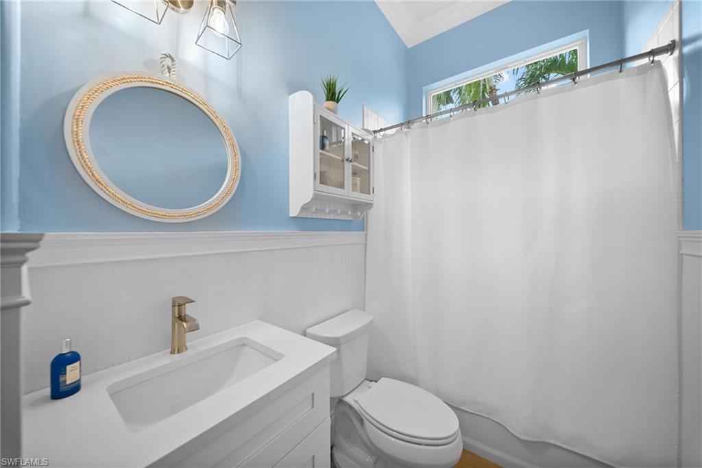 Bathroom featuring a white vanity with integrated sink, brushed gold-tone faucet, and a decorative round mirror