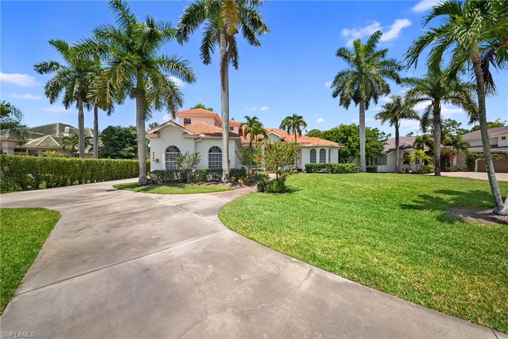 Mediterranean-style residence featuring a terracotta tile roof, arched windows, and a light-toned stucco exterior