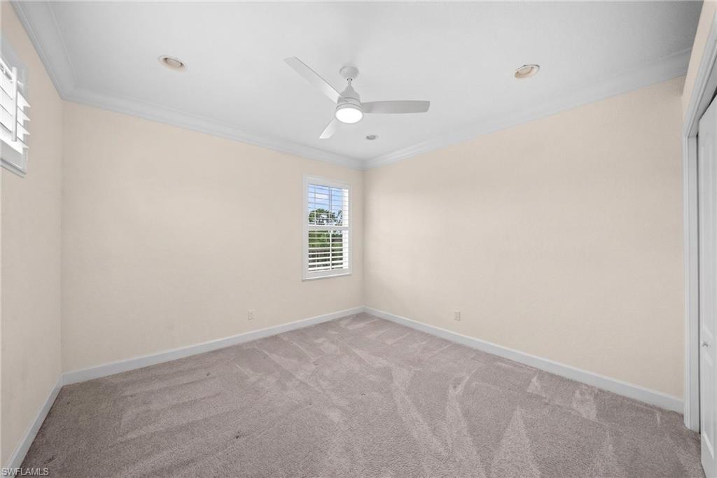 Spacious room featuring neutral-toned walls, recessed lighting, and crown molding