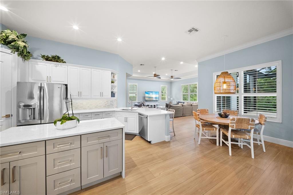 Kitchen featuring white cabinetry, stainless steel appliances, a center island with light-toned cabinetry, and quartz countertops