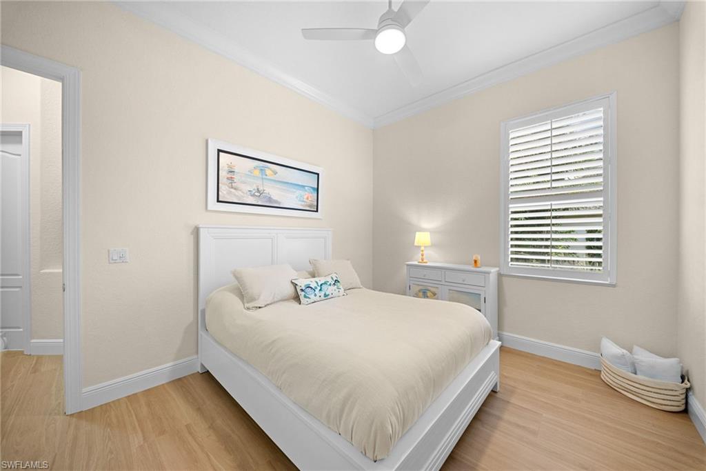 Bedroom featuring wood-finish flooring, a ceiling fan, crown molding, and plantation shutters