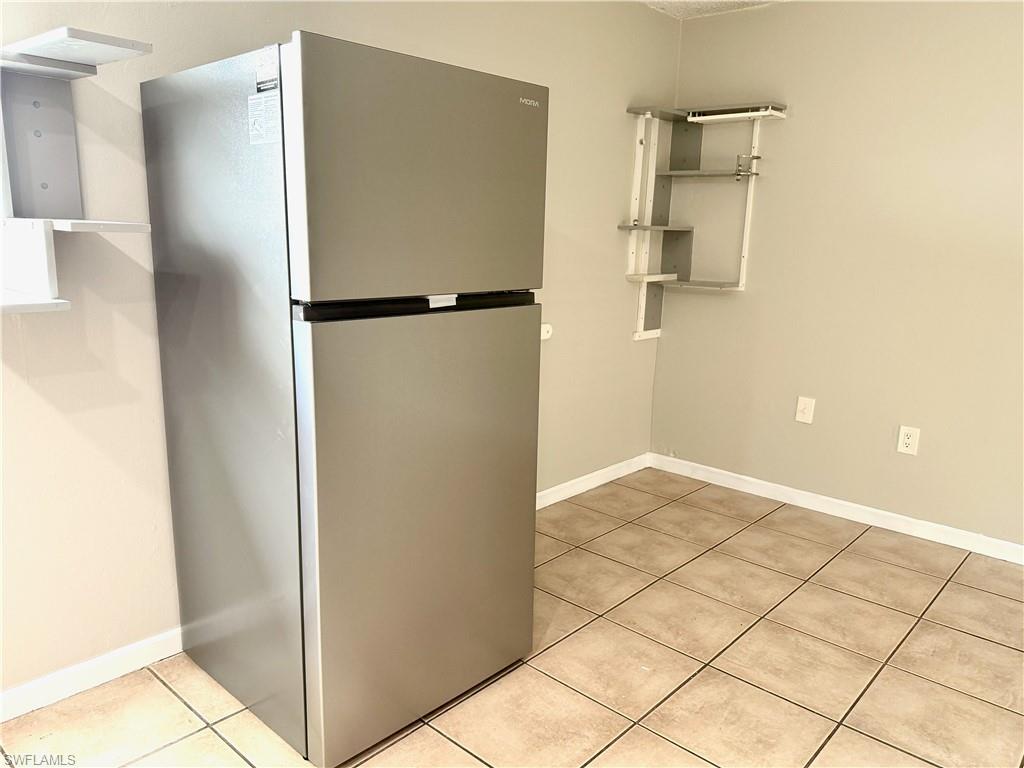 Stainless steel refrigerator, tile flooring, and wall-mounted shelving