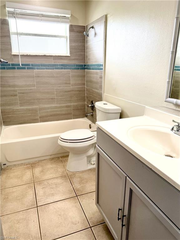 Bathroom featuring a single vanity with a white countertop and gray cabinetry, a white toilet, and a combination shower and tub