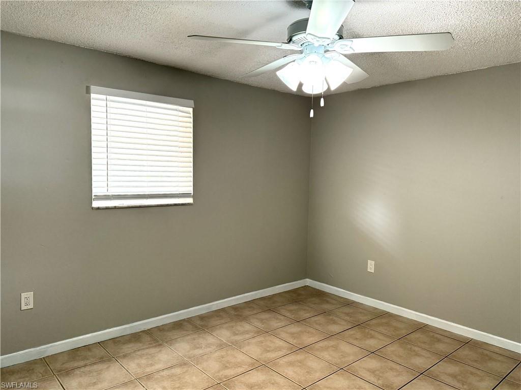 Room featuring square tile flooring, neutral wall paint, and a textured ceiling