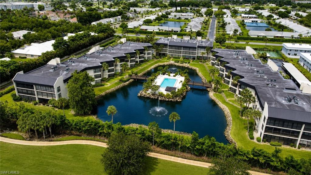 Expansive community pool centrally positioned within a tranquil water feature, surrounded by multi-story residential buildings