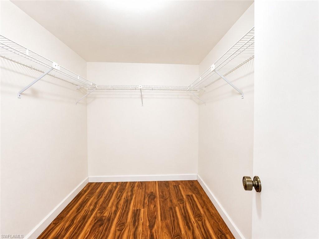 Walk-in closet featuring wood-finish flooring, white baseboards, white walls, and built-in wire shelving