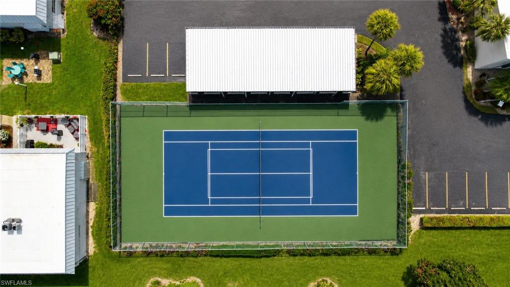 Fenced tennis court featuring a blue playing surface and green surrounds