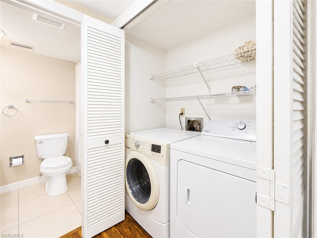Dedicated laundry area featuring a white front-load washer and dryer, wire shelving, and wood-finish flooring