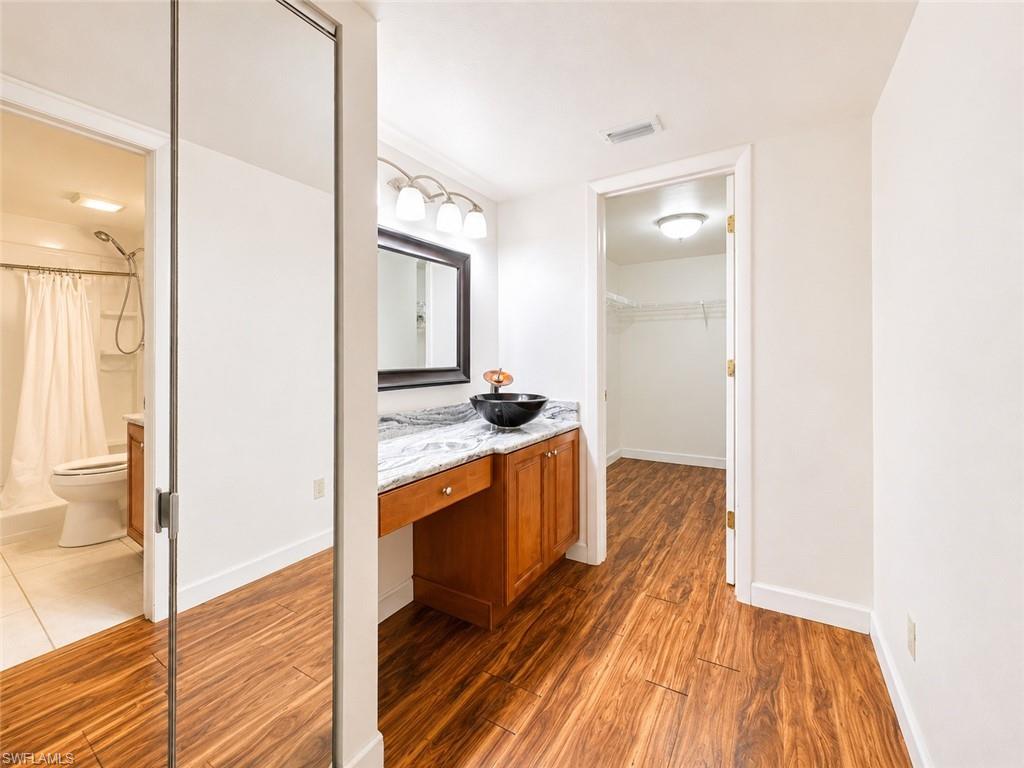 Bathroom vanity with a vessel sink, a granite countertop, and wood cabinetry
