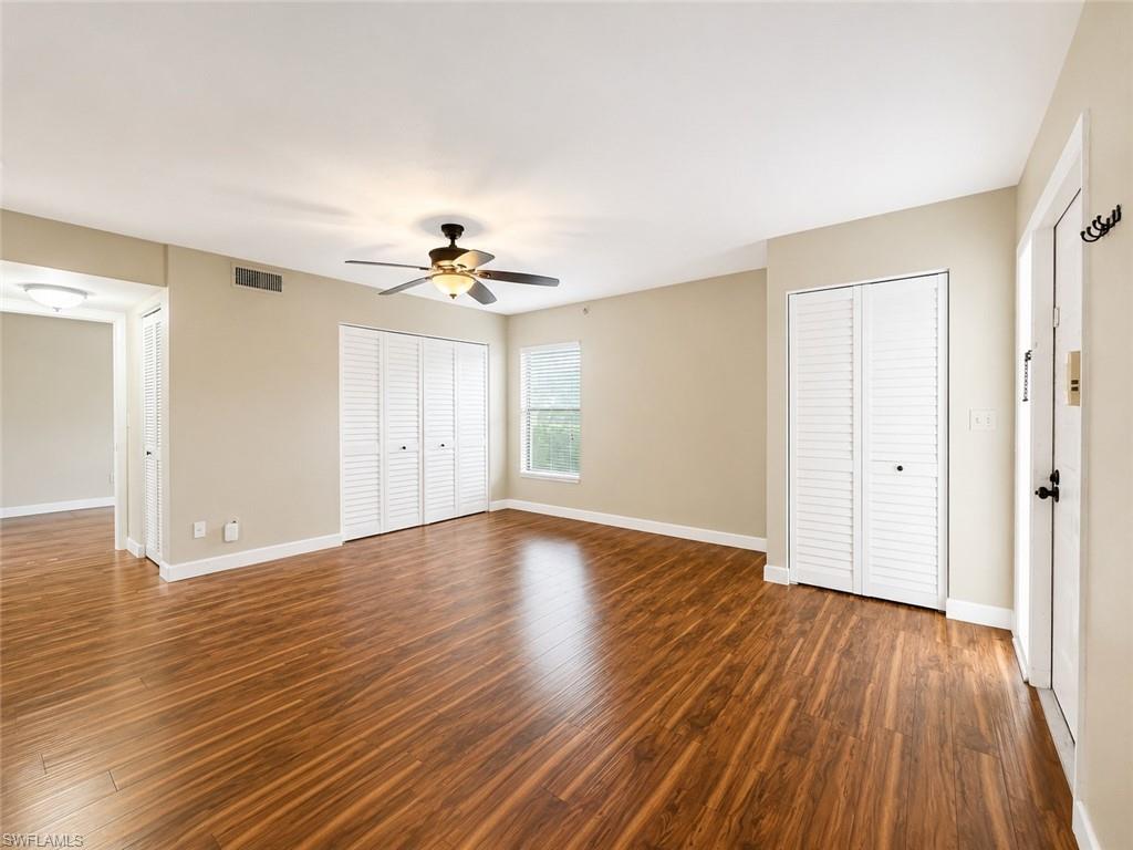 Spacious room featuring wood-finish flooring, neutral-toned walls, and white baseboards