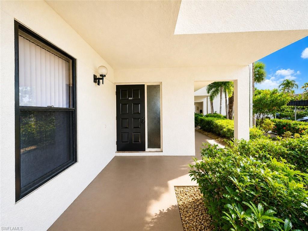 Entryway featuring a paneled door, a sidelight, a wall-mounted light fixture, and a window with vertical blinds