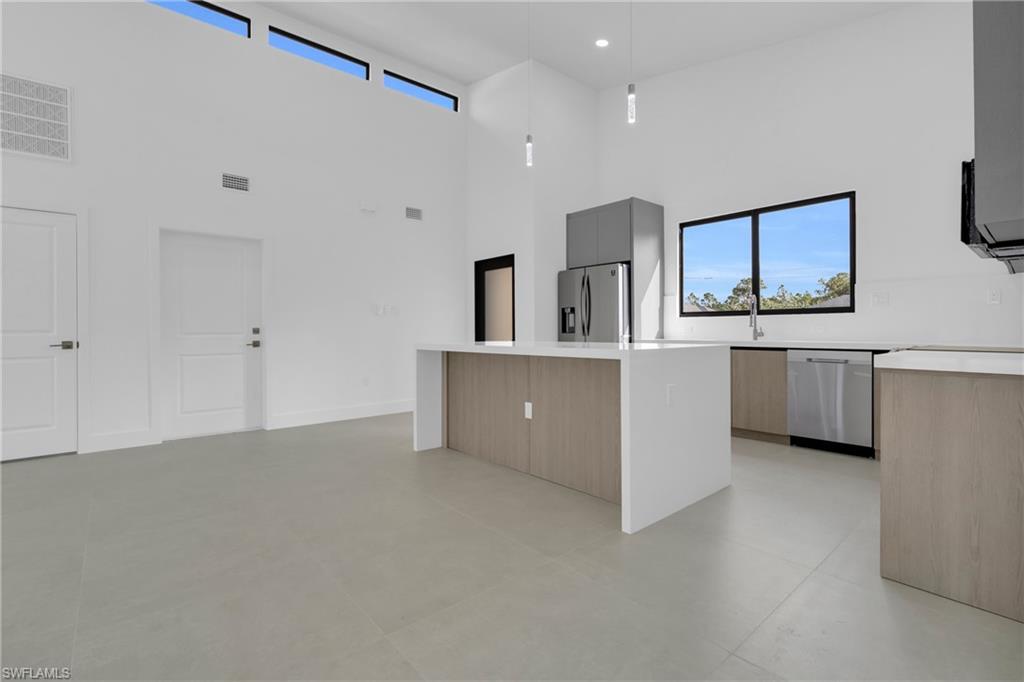 Kitchen with a center island, modern cabinets, decorative light fixtures, stainless steel appliances, and light brown cabinets
