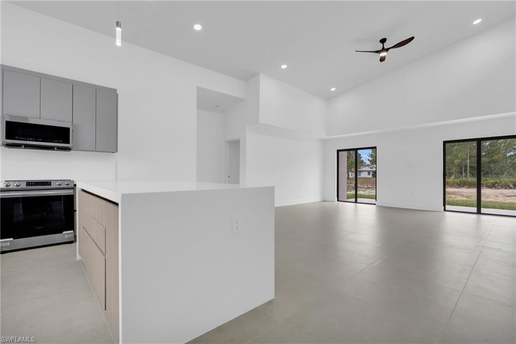 Kitchen featuring appliances with stainless steel finishes, modern cabinets, a high ceiling, ceiling fan, and open floor plan