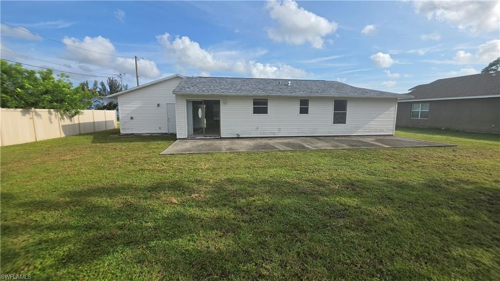 Spacious backyard featuring a concrete patio, sliding glass door access to the interior, and a privacy fence