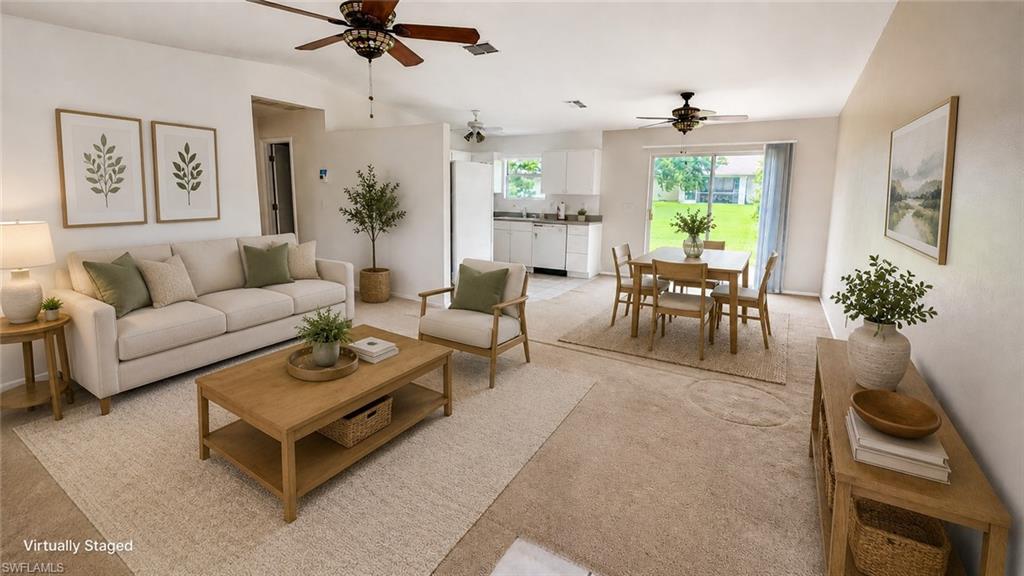 Open-concept living area featuring light-toned carpeting, ceiling fans, and a dining space with patio door access