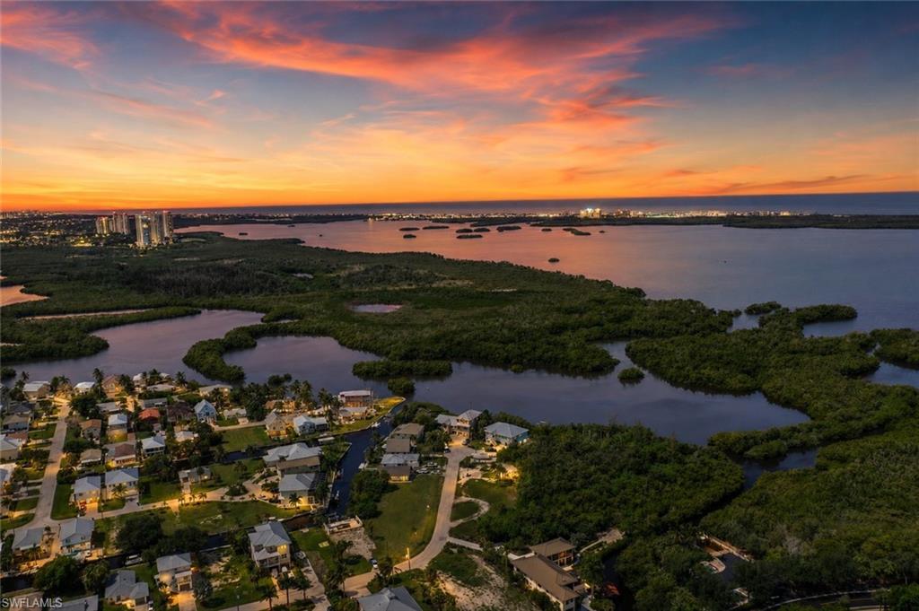 Waterfront community with canal access, surrounded by diverse vegetation, and illuminated by a vibrant sunset backdrop