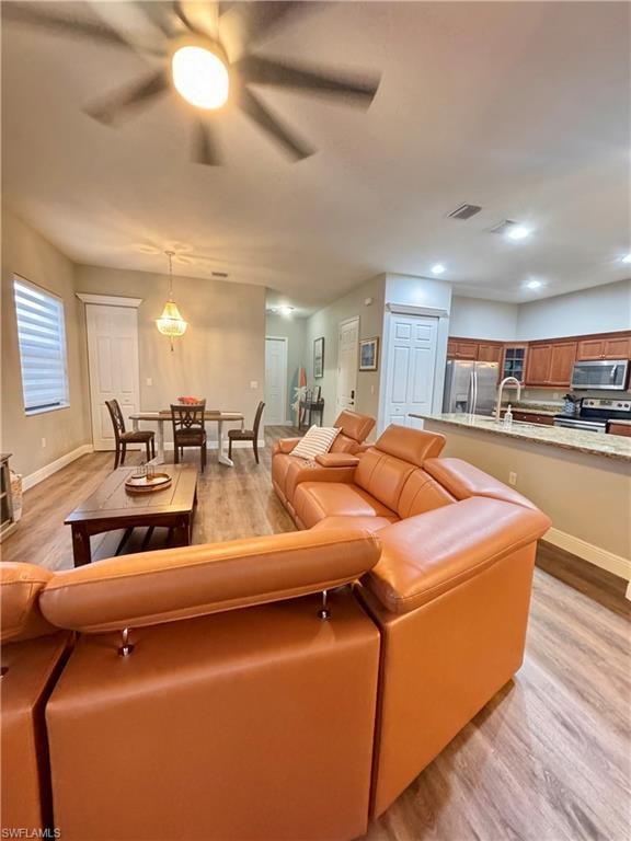Open-concept living area featuring wood-finish flooring, recessed lighting, and a ceiling fan