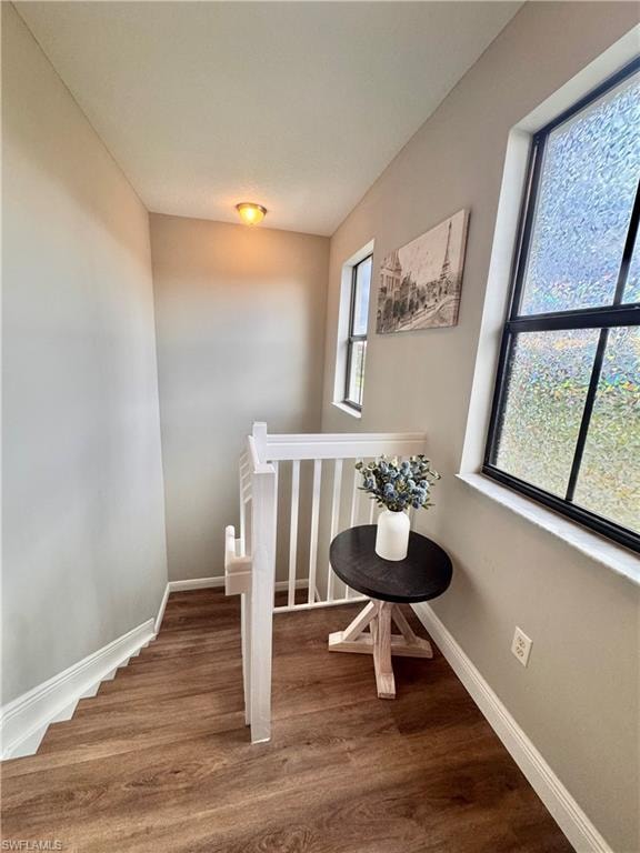 Staircase featuring wood-finish flooring, white balusters, and a white handrail