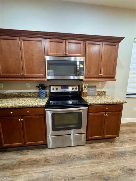 Kitchen featuring wood cabinetry, light-toned countertops, and stainless steel appliances