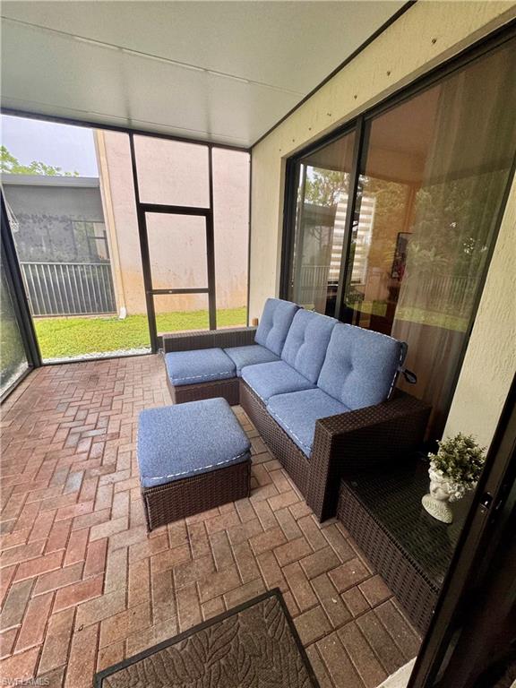 Screened patio featuring herringbone pattern brick pavers, a white overhead ceiling, and sliding glass door access to interior spaces