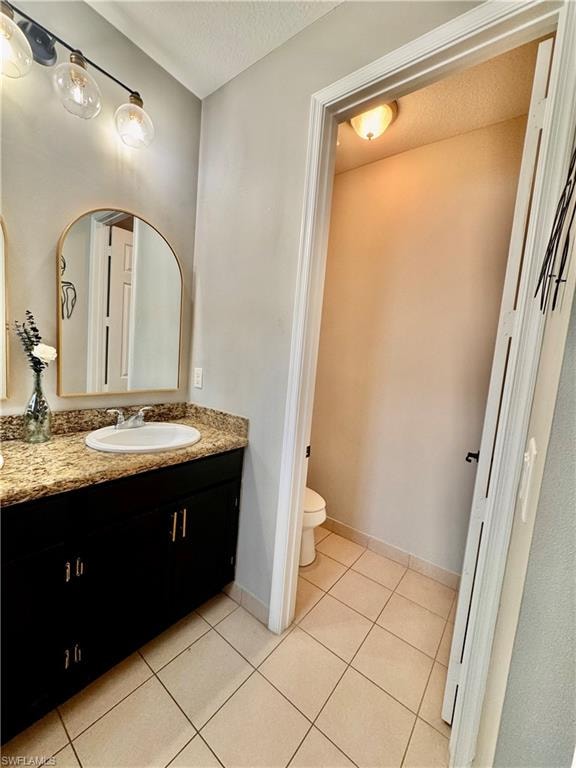 Bathroom featuring a dark wood-finish vanity with a speckled countertop, a white drop-in sink, and a multi-bulb vanity light fixture