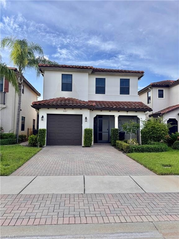 Stucco exterior featuring a tile roof, paver driveway, single-car garage, and established landscaping with hedges and a palm tree