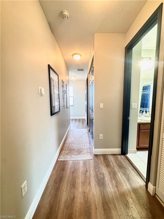 Hallway with wood-finish flooring and light neutral wall paint