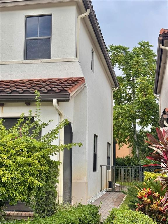 Stucco exterior with terracotta-style roof tiles and white gutters