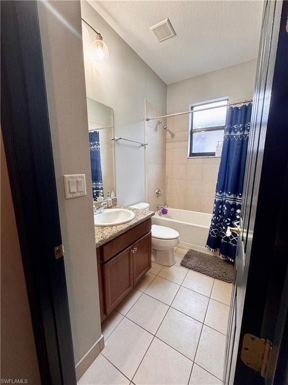 Full bathroom with tile flooring, a wood-finish vanity with a stone-look countertop, and a shower-tub combination with tile surround