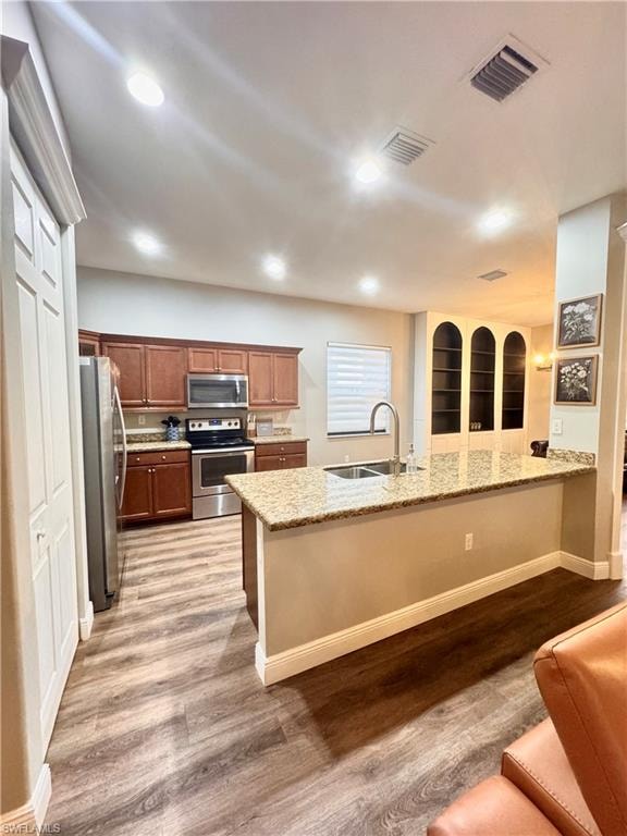 Kitchen featuring wood-finish flooring, recessed lighting, and a breakfast bar with a granite-style countertop