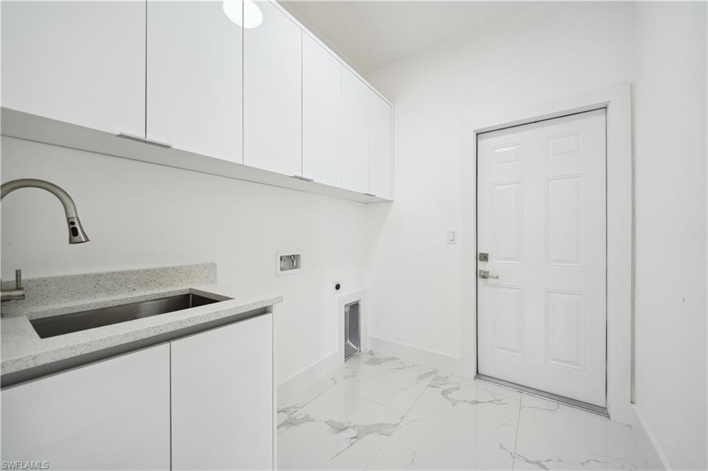 Laundry area featuring white cabinetry, a sink with a stainless steel faucet, and a light-colored countertop